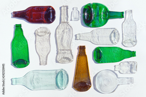Composition of molten, flat bottles of different colors on white background