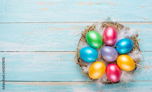 Easter colored eggs in a nest on a wooden background with space