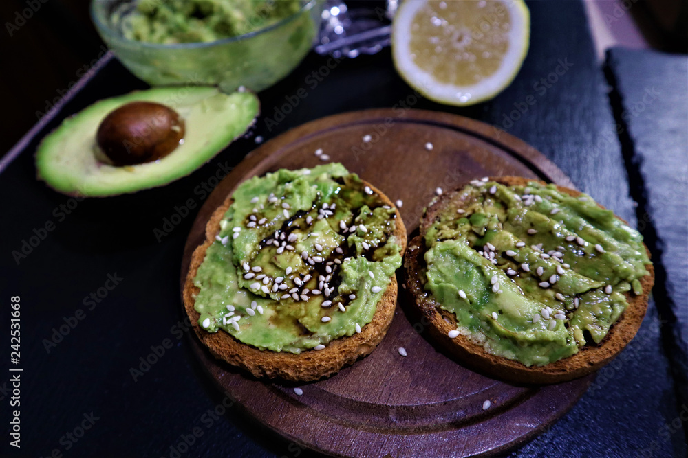 Avocado toast , overhead viewy avocado sandwich on toast bread made with fresh avocado paste on the black background Avocado toast , overhead viewy avocado sandwich on toast bread made with fresh avocado paste on the black background