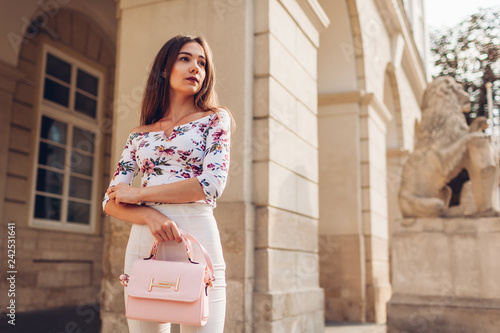 Young woman wearing beautiful outfit and accessories and shoes outdoors. Girl holding stylish handbag. Fashion model