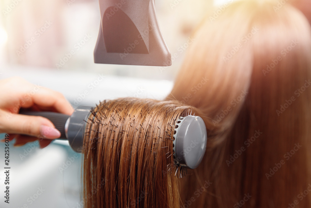 © Parilov - Drying styling long Shine brown hair with dryer and round brush after Spa care. Master hand