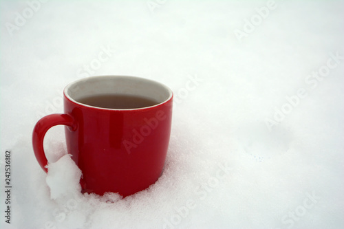 Red mug with tea in the snow Winter morning Copy space