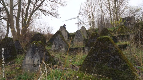 View of a woman with a windmill in the background looking at the Siegfried Line also known as Dragon Teeth, German defensive lines during the Second World War near the city of Aachen. photo