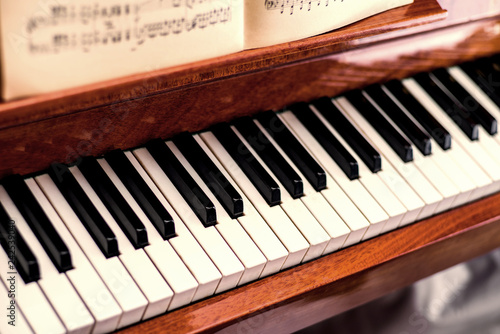 Piano keyboard with sheet music and with selective focus and blurred background.