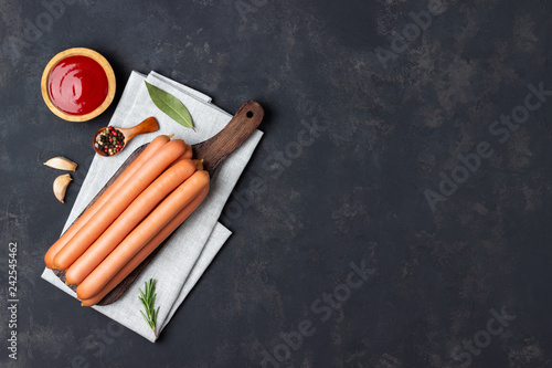 Raw frankfurter sausages with ketchup on cutting board. Top view. Copy space for text.