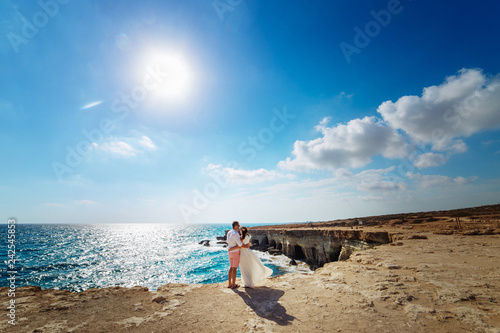 young couple on a rock looking at the sea