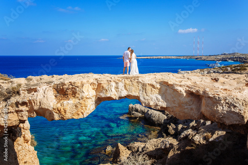 young couple on a rock looking at the sea