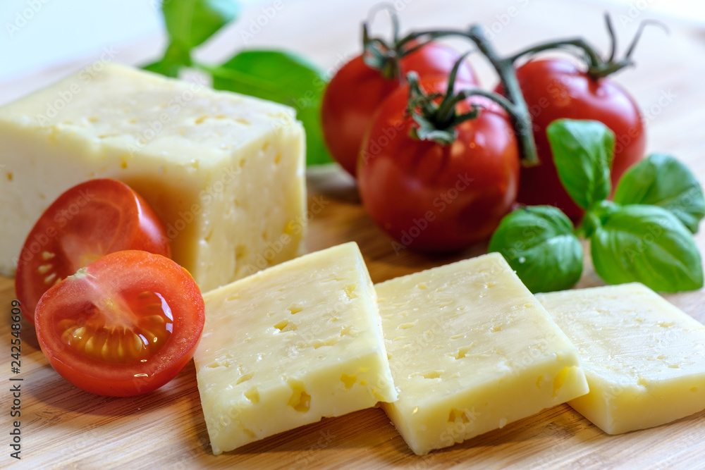 Cheese, cherry tomatoes and basil on wooden surface, selective focus