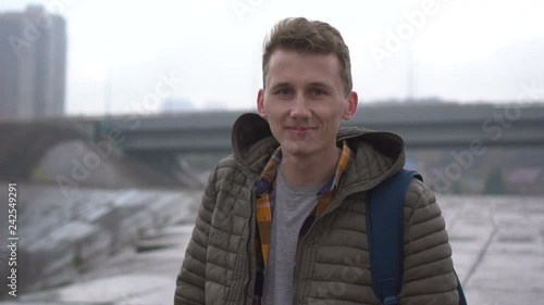 Portrait of handsome cute caucasian man outdoor. Close-up. Serious young man looking at camera photo