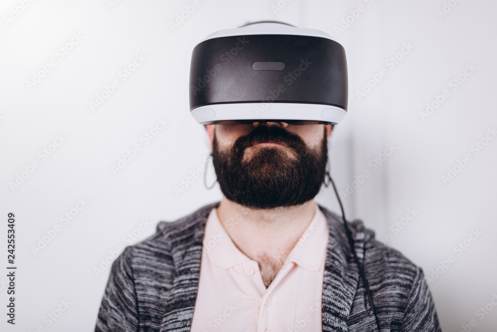 Adult bearded man gaming in visual futuristic digital 3d device. Technology, virtual reality glasses, innovation concept Adult bearded man gaming in visual futuristic digital 3d device. Technology, virtual reality glasses, innovation concept