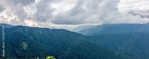 Panoramic view of a mountain range covered with forest in thick clouds photo