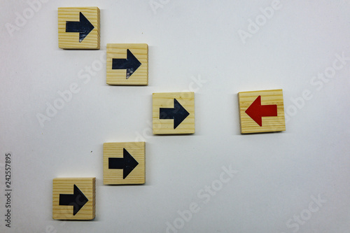 Hand picked red wooden blocks with white arrows facing opposite to the black arrows. With different concepts to other people. Going for success.