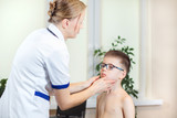 Lekarka w gabinecie lekarskim podczas badania migdałków u chłopca w okularach