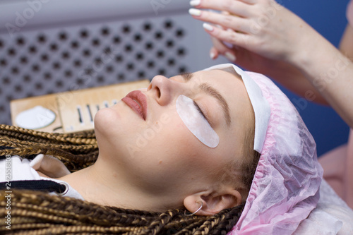 Eyelash Extension Procedure. Woman face with Long false Eyelashes. Close up macro shot of fashion eyes visagein in beauty salon photo