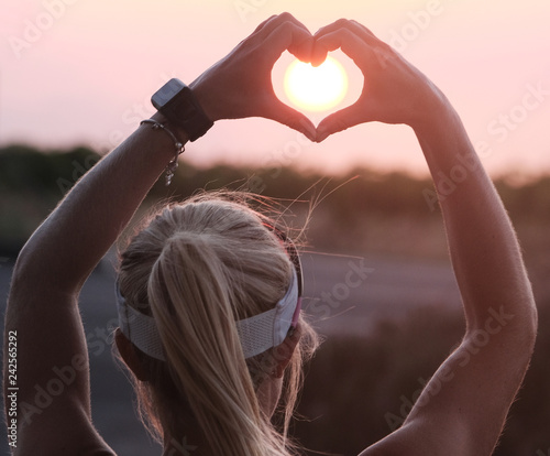 female making a heart sign with her hands for Valentines with sun in the middle