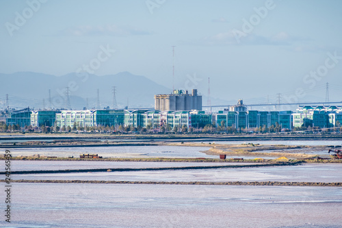 Office buildings on the shoreline of San Francisco bay, salt evaporation ponds in the foreground, Redwood City, California photo