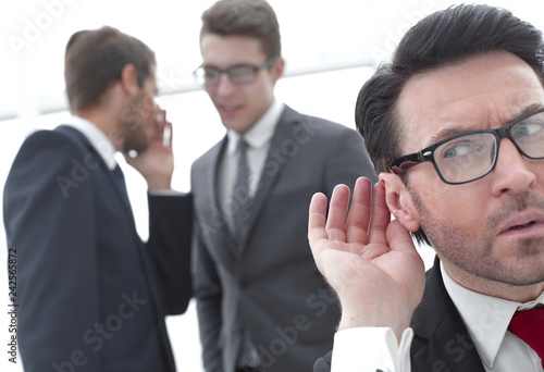 close up.businessman eavesdropping on conversation between colleagues photo