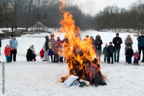 Holiday Carnival. Burning stuffed at Shrovetide outdoors in the snow. Сampfire gatherings bonfire in the snow. Sitting around the campfire, bred right in the snow.