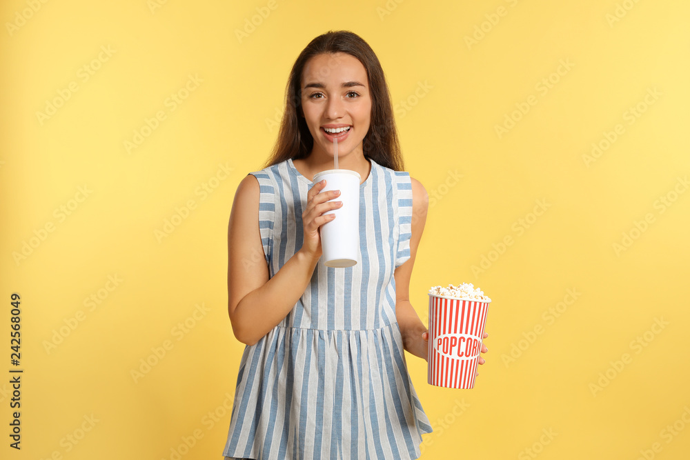 Woman with popcorn and beverage during cinema show on color background Woman with popcorn and beverage during cinema show on color background