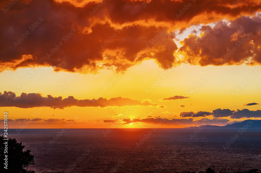 Dramatic sunset above the sea. Mountains and sea in golden color.