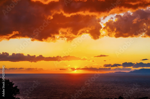 Dramatic sunset above the sea. Mountains and sea in golden color.