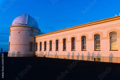 View of the facade of the main building of the historical Lick Observatory (completed in 1888) at sunset; visitors' shadows projected on its walls; San Jose, south San Francisco bay area, California