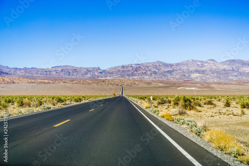 Driving through the Devil's cornfield area of Death Valley National Park; colorful rocky mountains in the background; California