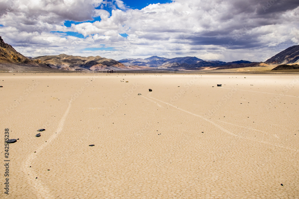 Moving rocks and their tracks at the Racetrack Playa; mountains and clouds scenery in the background; Death Valley National Park, California Moving rocks and their tracks at the Racetrack Playa; mountains and clouds scenery in the background; Death Valley National Park, California