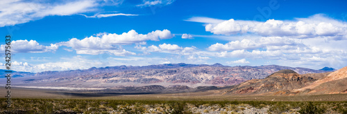 Panoramic landscape of colorful mountains and volcanic areas in Death Valley National Park; blue sky and white clouds in the background; California