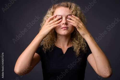 Young beautiful woman with curly blond hair covering eyes