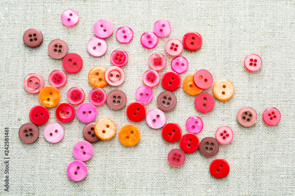 Lots of colorful sewn-on buttons of different colors on a linen lightweight natural fabrics Lots of colorful sewn-on buttons of different colors on a linen lightweight natural fabrics