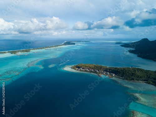 Luxury overwater villas with coconut palm trees, blue lagoon, white sandy beach at Bora Bora island, Tahiti, French Polynesia