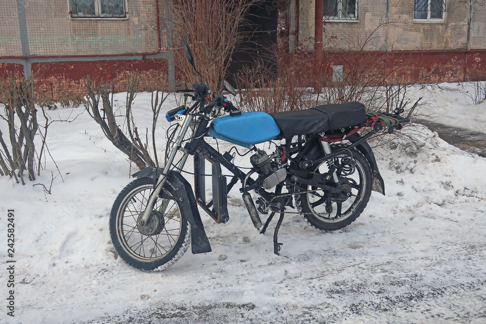Retro moped parked in the snow on the side of the road.