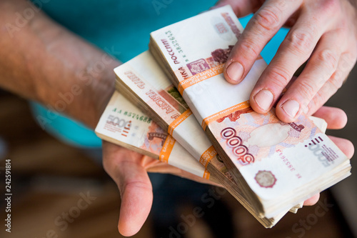 Hand holding cash paper money.banknote exchange.Paying for service or bribe. financial Analytics, loans, cash, purchases, debts concept.Five-thousandth banknotes of the Russian ruble in a man's hand
