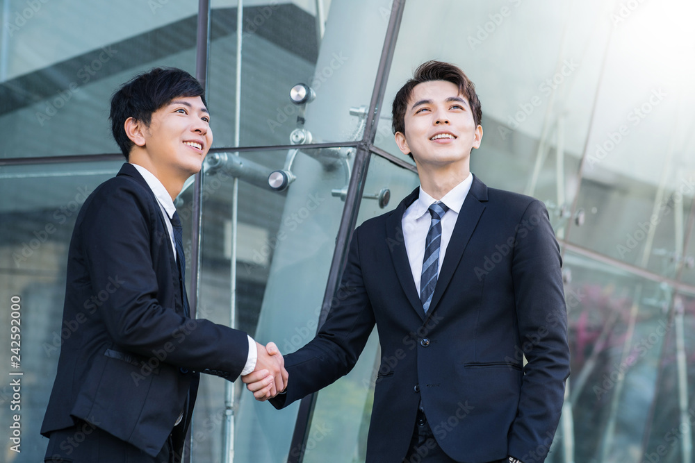 Two confident businessmen shaking hands and smiling Two confident businessmen shaking hands and smiling