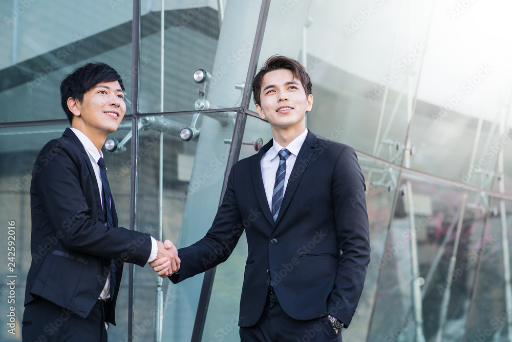 Two confident businessmen shaking hands and smiling Two confident businessmen shaking hands and smiling