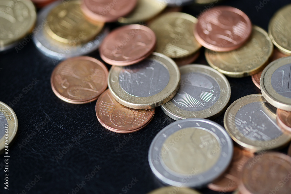 A pile of euro coins scattered on a dark surface close up A pile of euro coins scattered on a dark surface close up