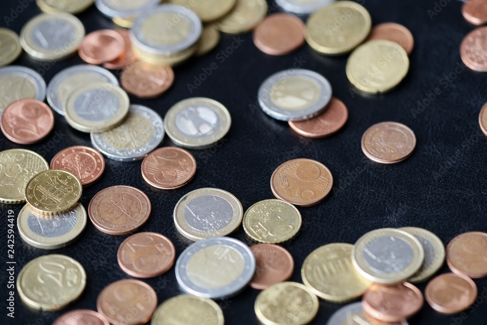 A pile of euro coins scattered on a dark surface close up A pile of euro coins scattered on a dark surface close up