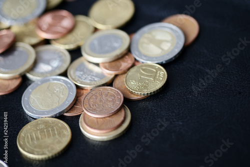 A pile of euro coins scattered on a dark surface close up