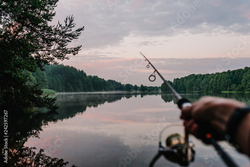 Fotografie Fisherman with rod, spinning reel on the river bank