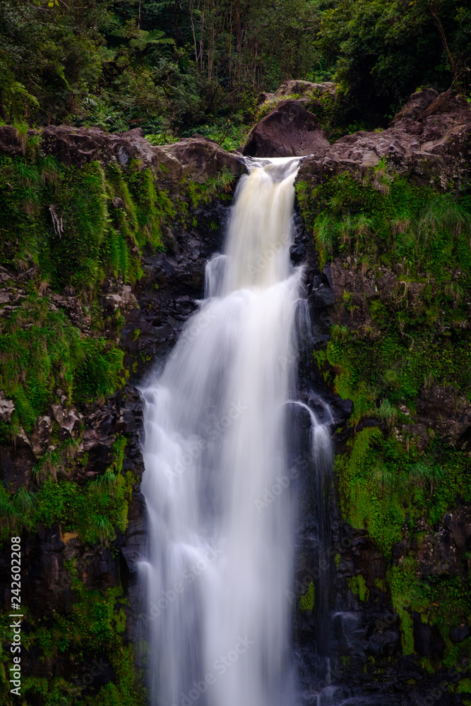 A long exposure of a waterfall flowing past green mossy rocks
