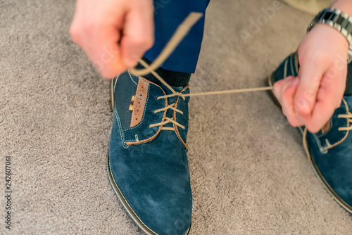 Man bonding up blue shoes laces.