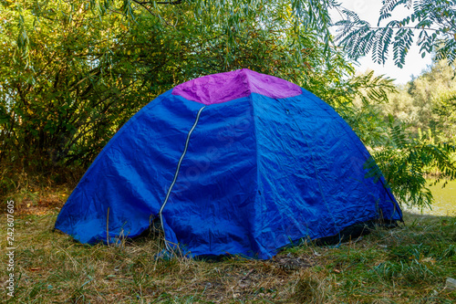 Blue camping tent in forest near a river