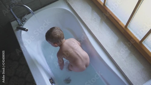two years old boy swims and plays in the bathroom and smiles beautifully.