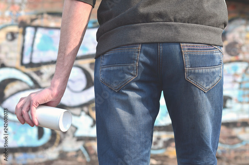 Graffiti artist with a spray can in his hand. Back view photo