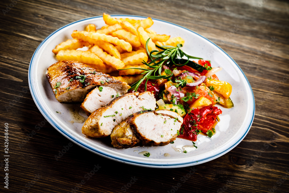 Grilled chicken fillet with french fries on wooden background Grilled chicken fillet with french fries on wooden background