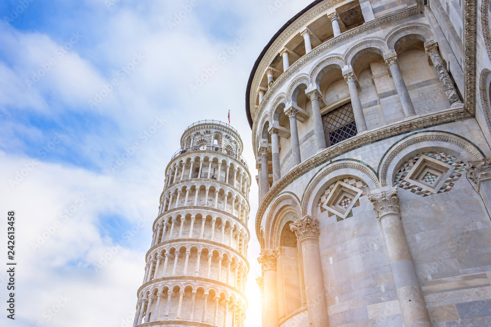 Leaning Tower of Pisa with a sun flare at sunset.