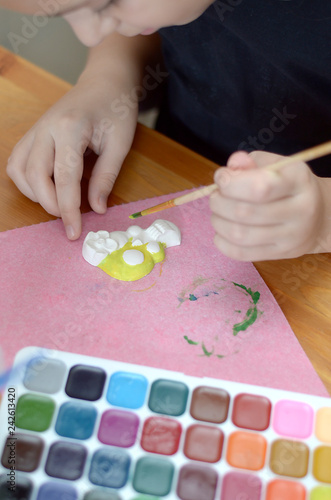 the girl draws with a brush on a plaster figurines colored with watercolors
