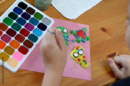 the girl draws with a brush on a plaster figurines colored with watercolors
