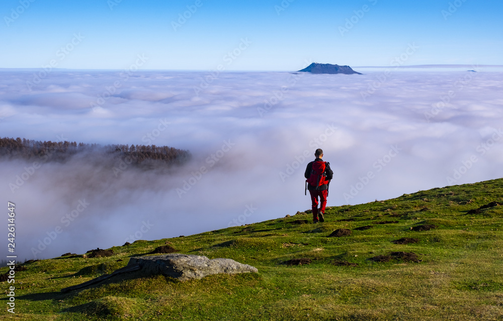 Man Traveler on mountain summit enjoying aerial view over clouds in Aiako Harriak Natural Park, Basque Country. Man Traveler on mountain summit enjoying aerial view over clouds in Aiako Harriak Natural Park, Basque Country.